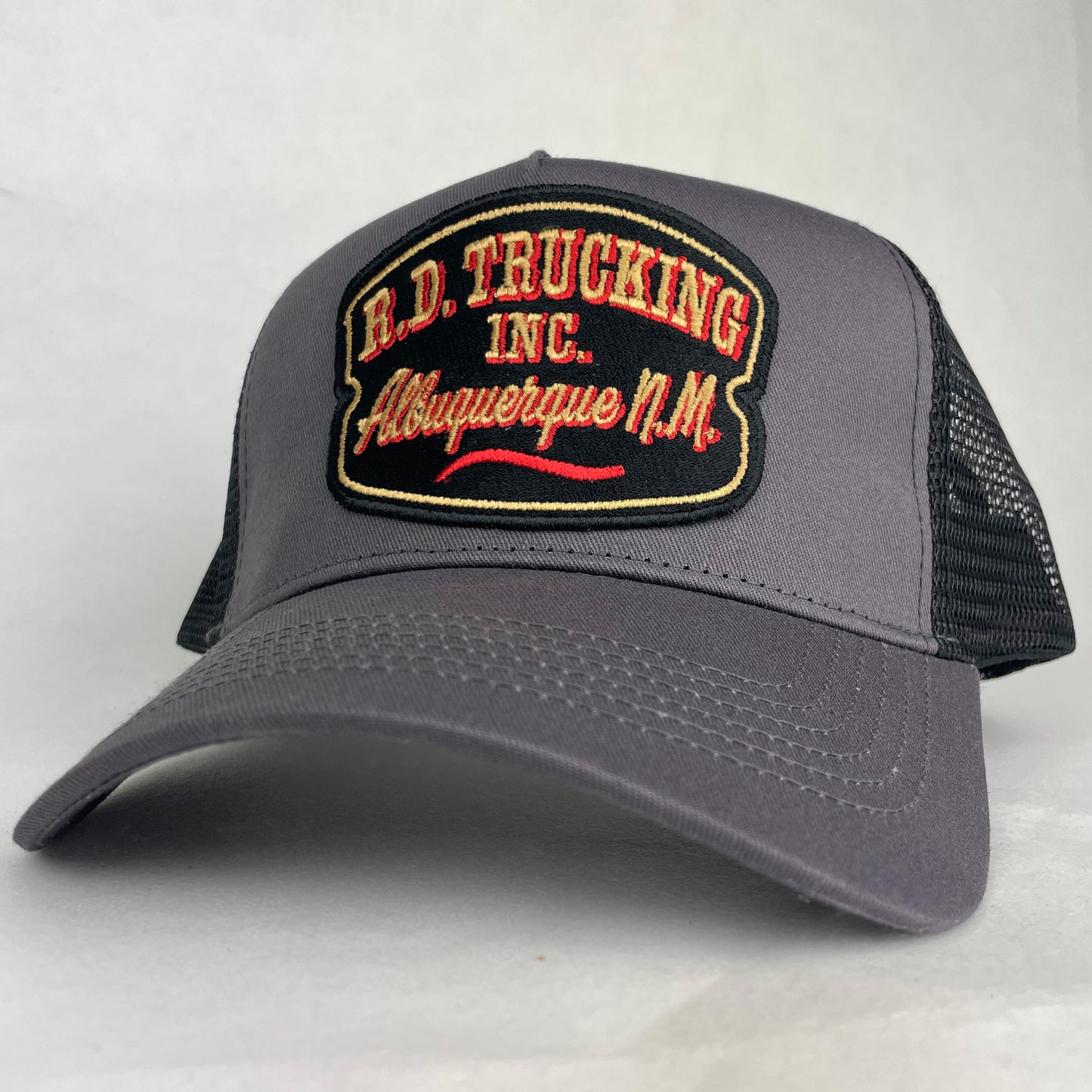 Gray trucker hat with embroidered patch on a light gray background